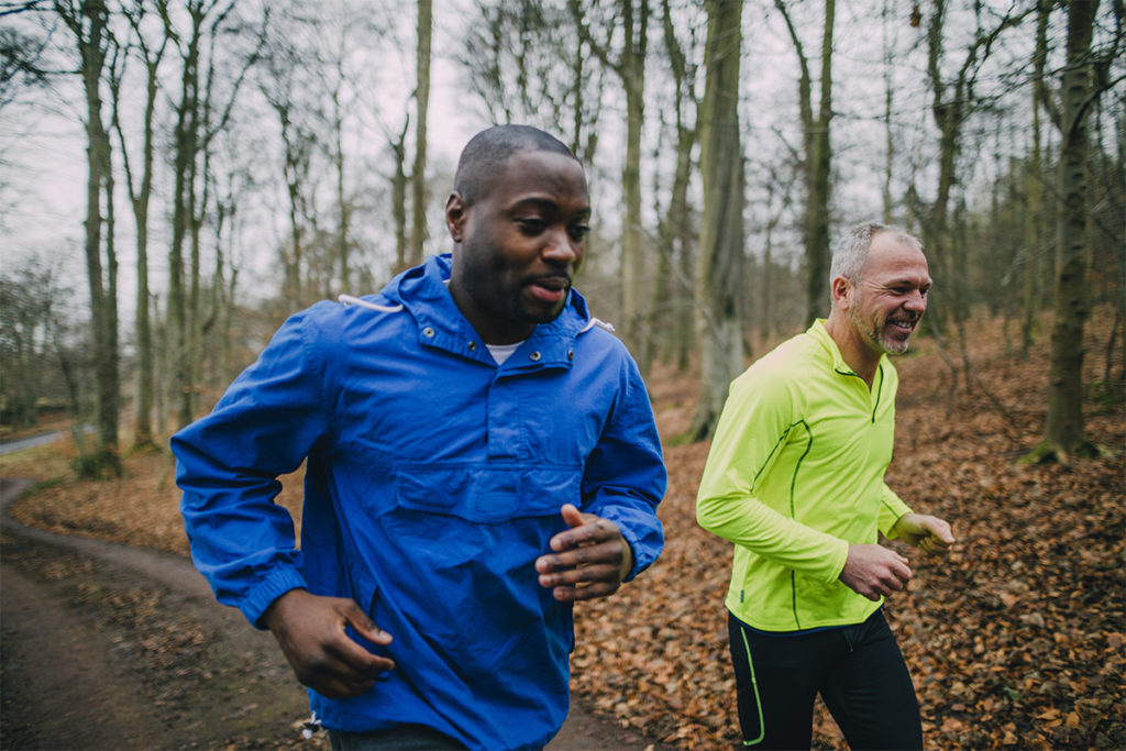 Two male friends jogging in a forest.