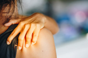 Personal rubbing their shoulder and rotator cuff