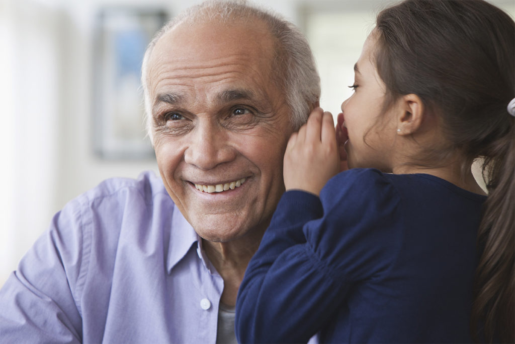 Little girl whispering in an older man's ear