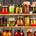 Jars in pantry with variety of pickled vegetables and preserved foods.