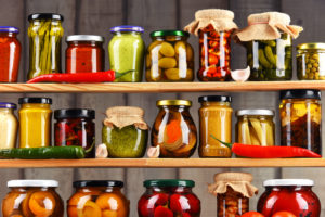 Jars in pantry with variety of pickled vegetables and preserved foods.
