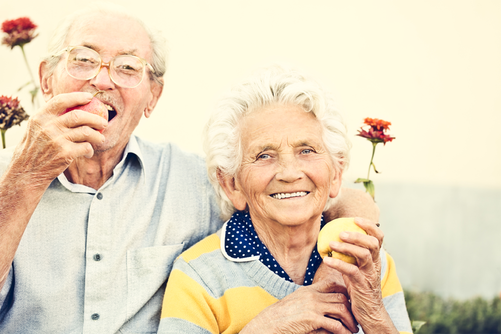 An older man and woman eating their 5 servings of fruits and vegetables