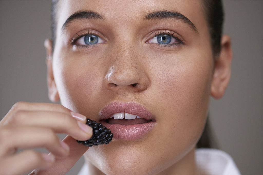 Person with clear skin eating berries