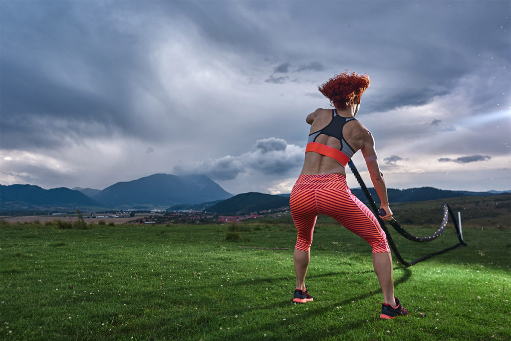 Woman doing battle rope HIIT workouts outside