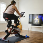 Woman using digital fitness on an indoor exercise bike