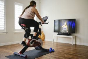 Woman using digital fitness on an indoor exercise bike