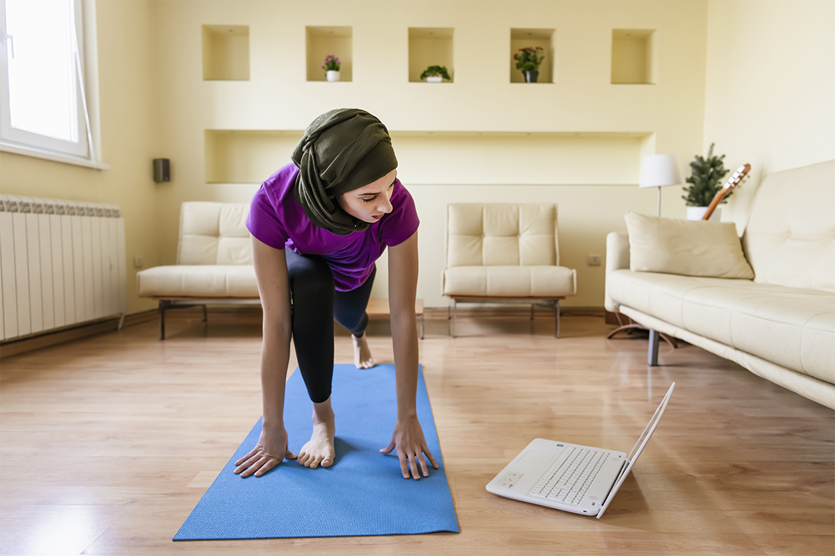 Woman taking digital fitness class from laptop