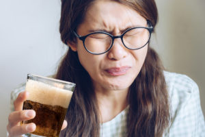 Woman drinking sweet drink with fructose and wincing