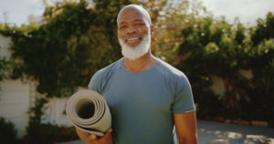 Cropped portrait of a happy senior man standing alone before a yoga session in his back garden