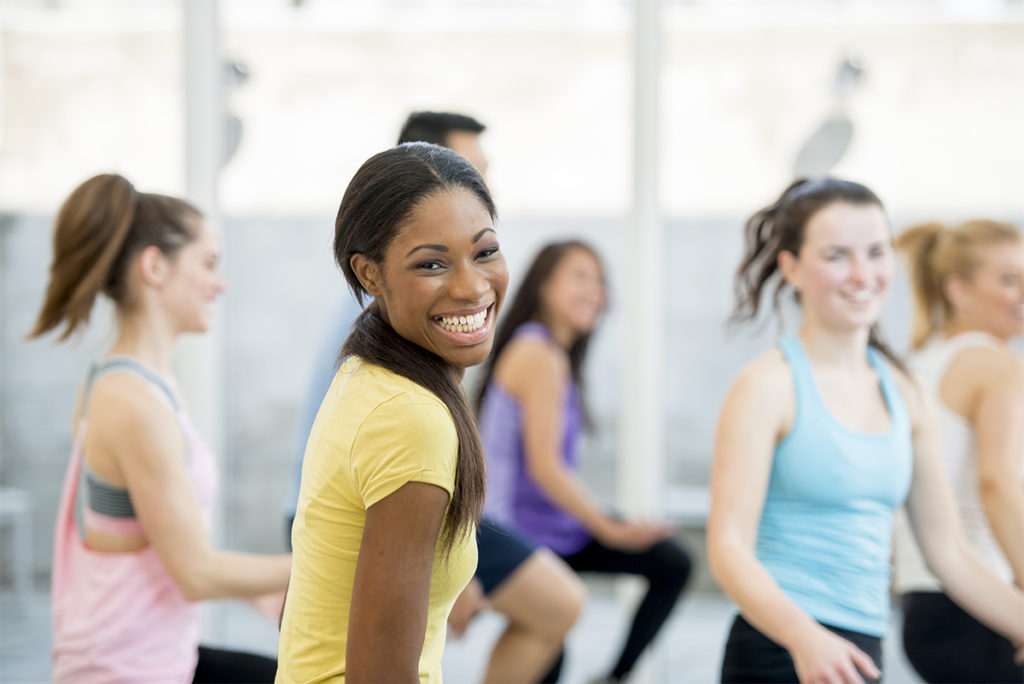 Woman smiling during an exercise glass to represent health and wellness