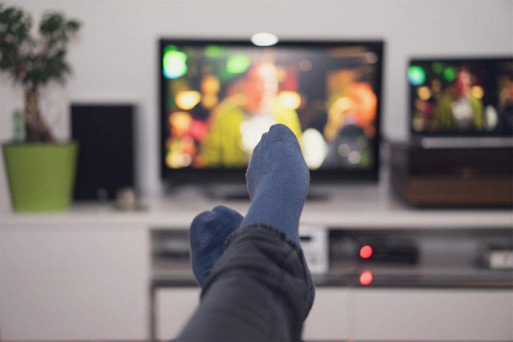 View of someone's foot as they lounge in front of a tv