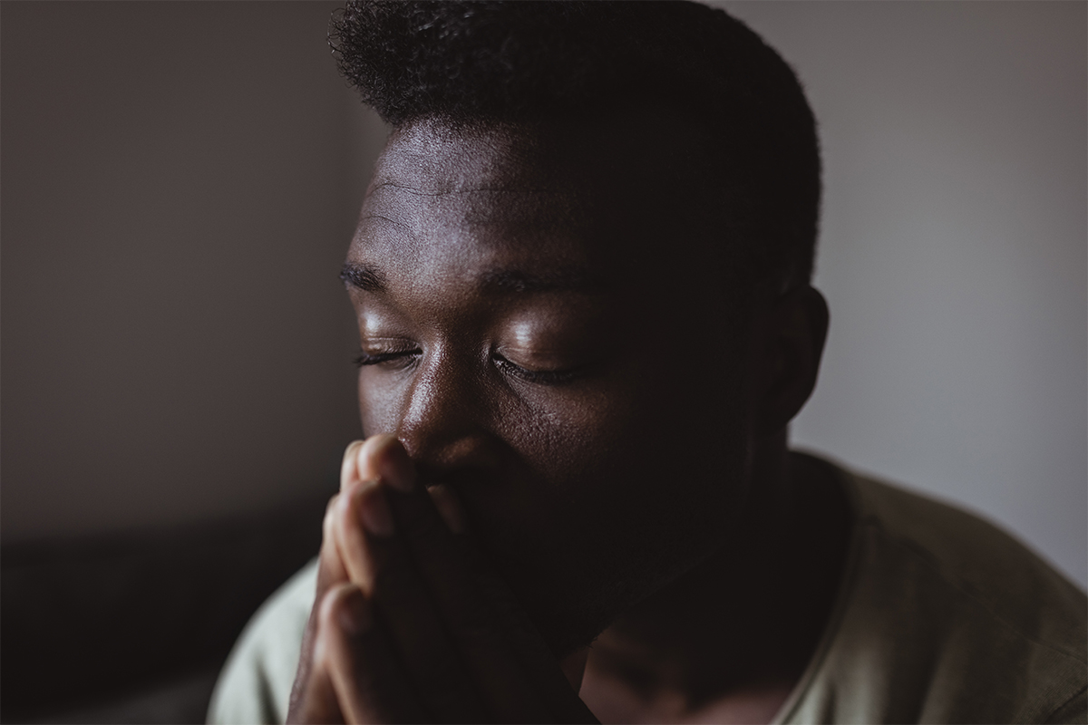 Person resting with eyes closed and hands clasped to represent mental health and wellness