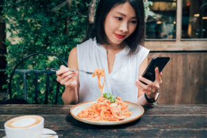 A woman overeating while distracted with a phone