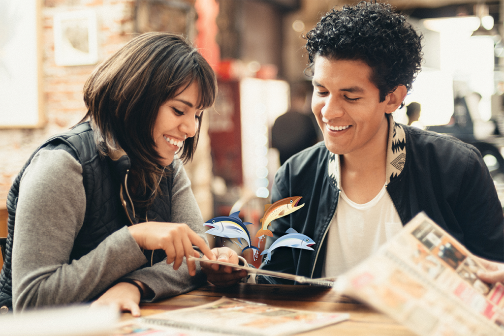 A man and woman looking at seafood nutrition in a menu