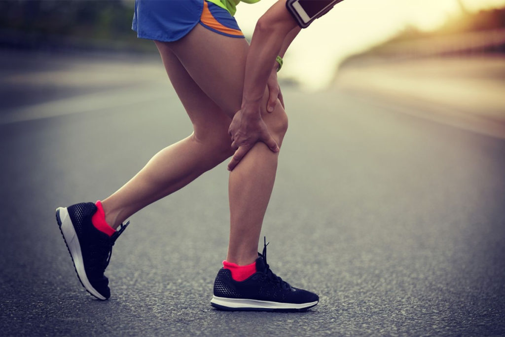 Person gripping their leg in pain on a run