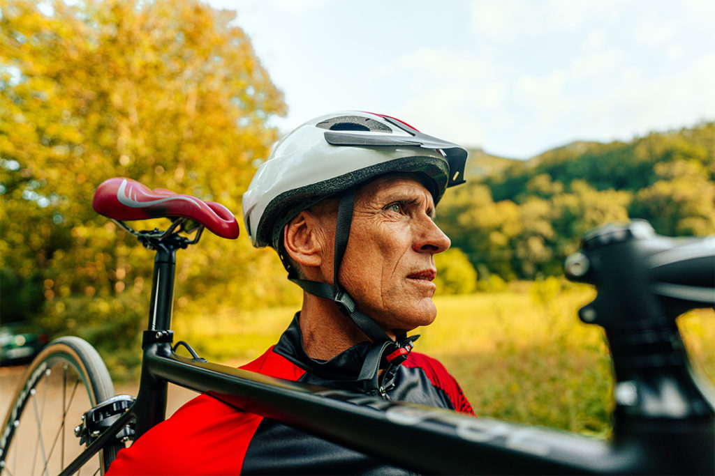 Older athlete carrying a bike