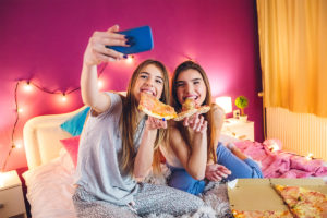 Teen girls showing smartphones and poor eating habits