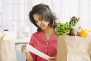 Woman looking at grocery food prices on receipt