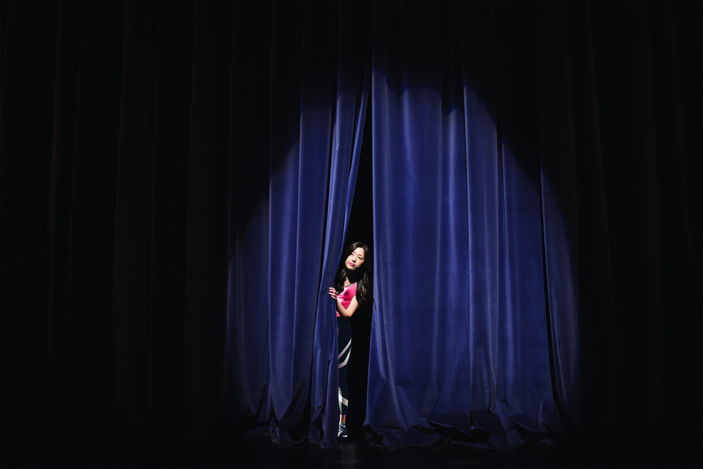 Introvert peeking out from behind a curtain on stage