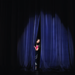 Introvert peeking out from behind a curtain on stage