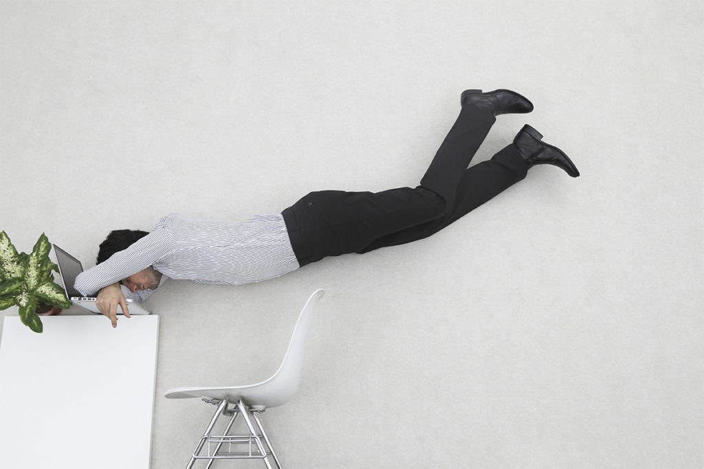 Man stressed and floating above desk to illustrate stress physiology and preventing holiday stress