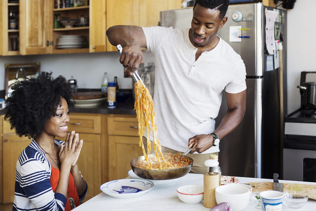 Man serving carbs in pasta form to woman