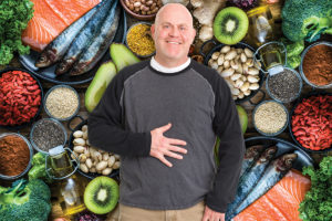 Man happily rubbing belly in front of fiber-rich foods to represent fiber benefits