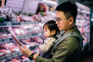 Father with toddler looking at plant-based meat substitutes at the store