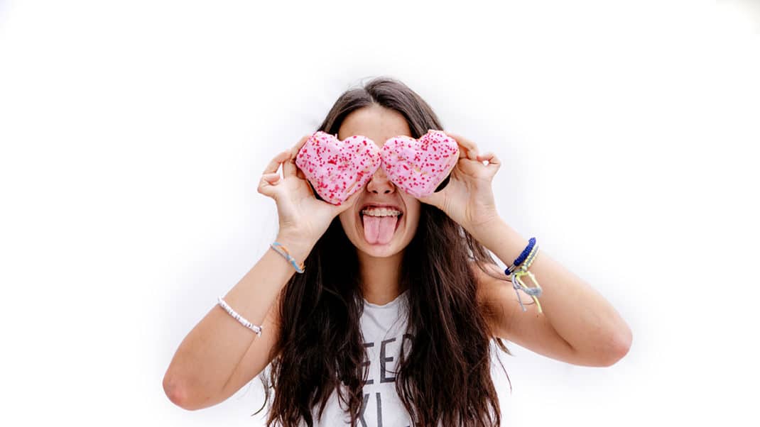 Girl sticking tongue and holding up cookies to show link between sugar and behavioral disorders