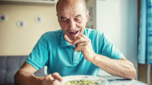 Older man putting in dentures before meal