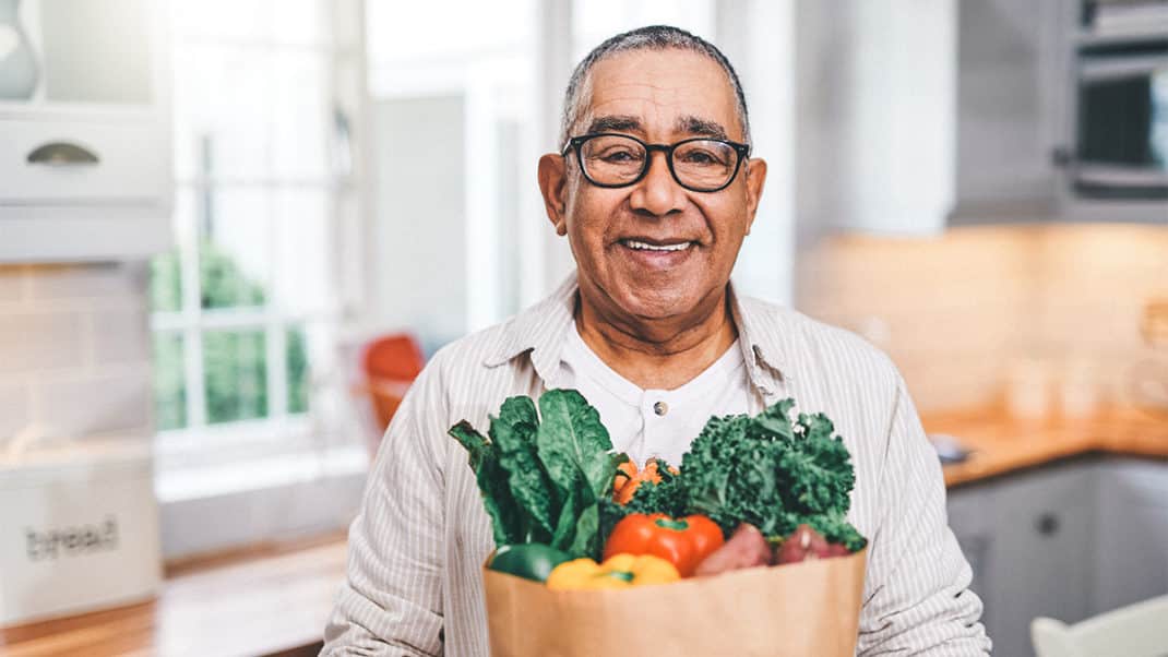 Older man with bag of produce to show link between diet and longevity