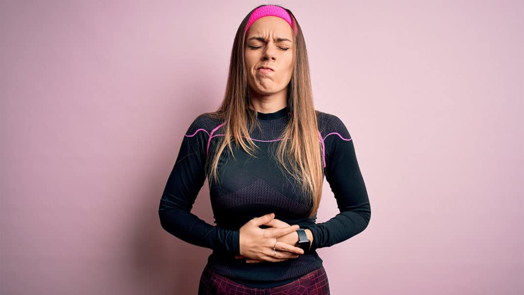 Woman holding her belly to show link between gut microbiome and athletic performance