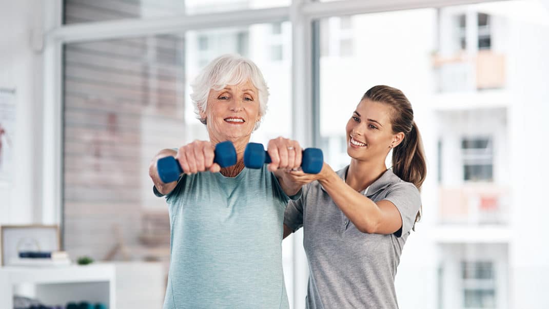 Trainer helping client with exercise and multiple sclerosis