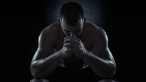 Dark image of man with head down to show use of exercise for depression