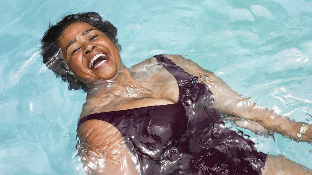 Woman in pool smiling big to show living a Ikigai lifestyle