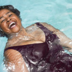 Woman in pool smiling big to show living a Ikigai lifestyle