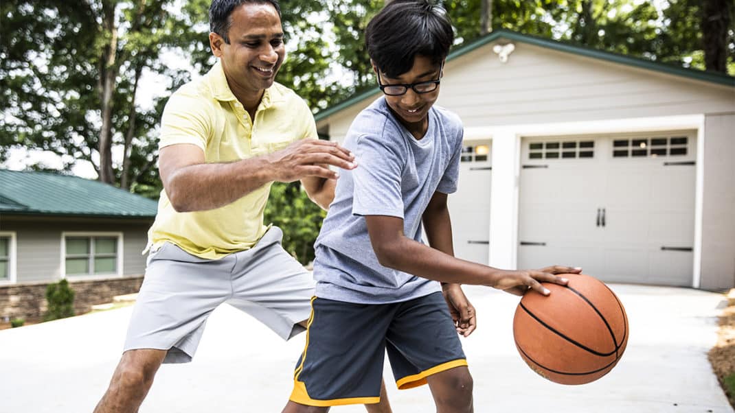 Father playing basketball with son to increase childhood activity