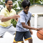 Father playing basketball with son to increase childhood activity