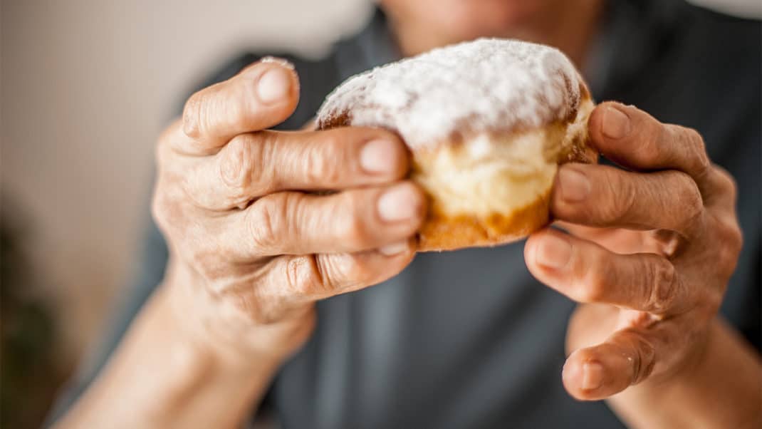 Older person holding a donut to show poor diet trends in older adults