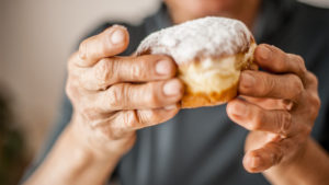 Older person holding a donut to show poor diet trends in older adults