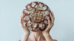 Person holding up bread with gluten in front of their face