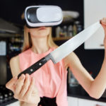 Woman with vr headset holding knife in kitchen to show virtual reality nutrition