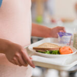 Child holding lunch tray to represent combatting hunger in America