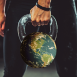 Person holding kettlebell that has the World transposed on it