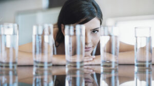 A woman looking at eight glasses of water