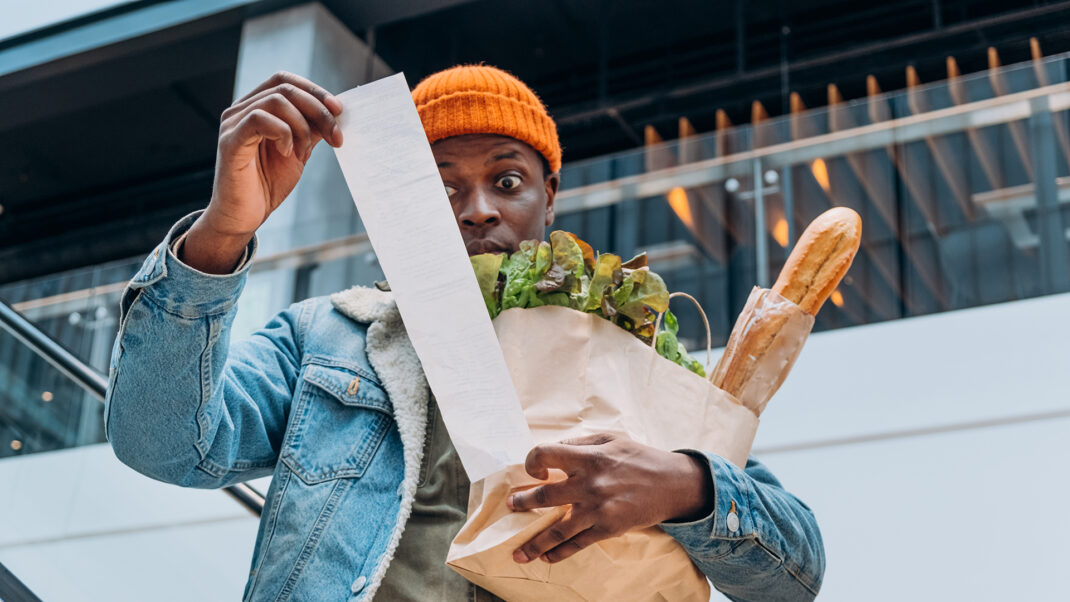 Man looking at grocery receipt to show rising food costs