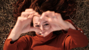 Woman holding hands up in the shape of heart to show self-compassion