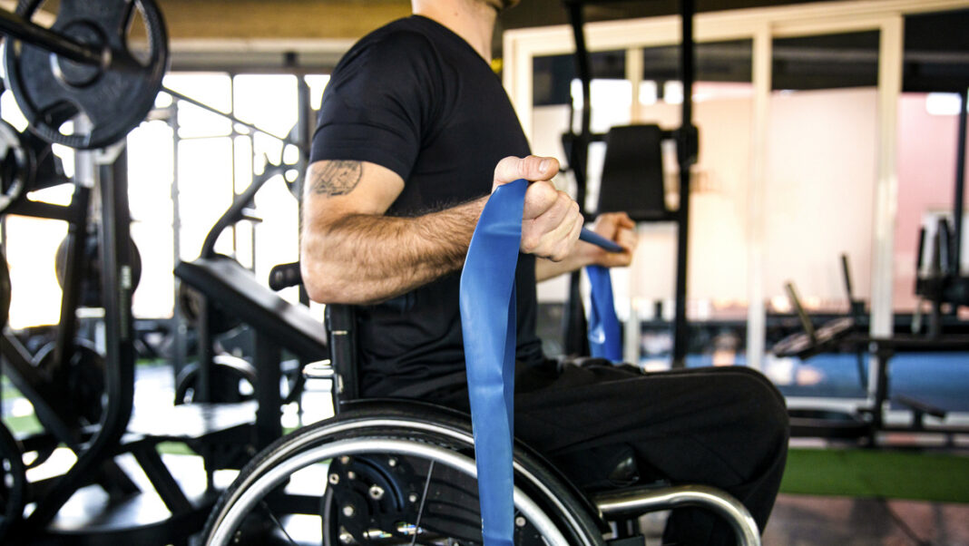 Middle-aged man in a wheelchair exercising in the gym stock photo