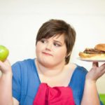Teen girl with overweight holding foods to represent adolescent obesity