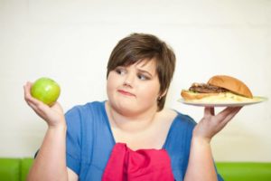 Teen girl with overweight holding foods to represent adolescent obesity